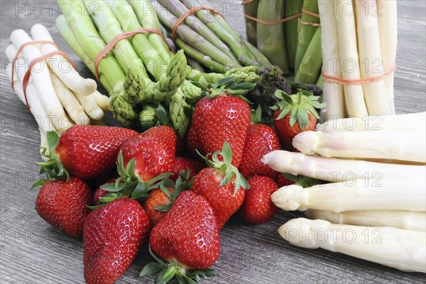 Green asparagus, white asparagus and fresh strawberries decorated on a rustic wooden table