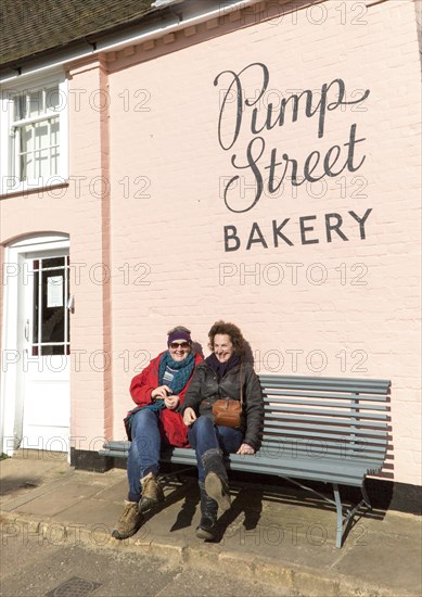 People sitting outside on sunny winter day Pump Street bakery, Orford, Suffolk, England, UK