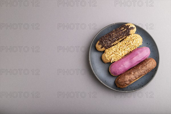 Set of eclair, traditional french dessert on blue ceramic plate on gray pastel background. top view, flat lay, copy space, still life. Breakfast, morning, concept