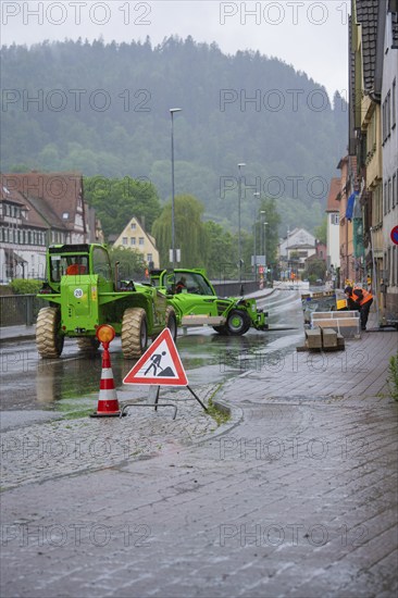 A construction site in a town in the rain, construction workers and excavators working on a wet road, Hermann Hesse railway construction site, Calw, Black Forest, Germany, Europe