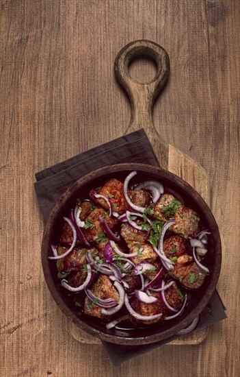 Fried meat, pork kebab, ketsi in a clay pan, with red onions and herbs, homemade, no people