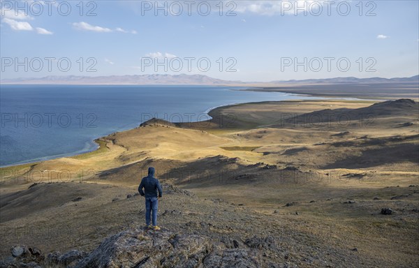 Tourist standing on a hill, view of mountain lake Song Kul, Naryn region, Kyrgyzstan, Asia