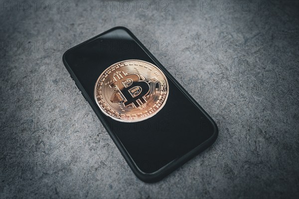 Symbolic image cryptocurrency, digital currency, golden coin Bitcoin on smartphone, dark background