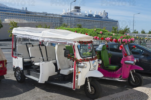 Two decorated tuk-tuks stand side by side, one white, the other pink, a large cruise ship can be seen in the background, Lisbon, Lisboa, Portugal, Europe