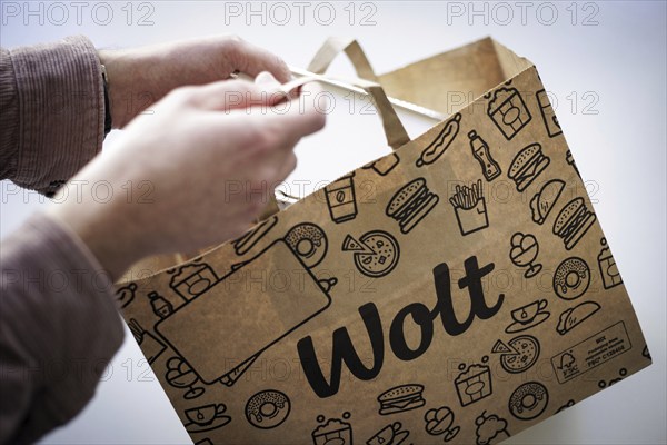 A person takes an order from a paper bag from the delivery service Wolt. Berlin, 28.03.2024