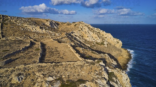 Drone shot, Archaeological site, Steep rocky coast above the blue sea, cloudy sky, Ruins of an acropolis, Arkasa, West coast, Karpathos, Dodecanese, Greek Islands, Greece, Europe