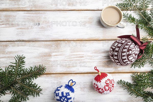 Christmas or New Year composition. Decorations, knitted balls, fir and spruce branches, cup of coffee, on a white wooden background. Top view, copy space, flat lay