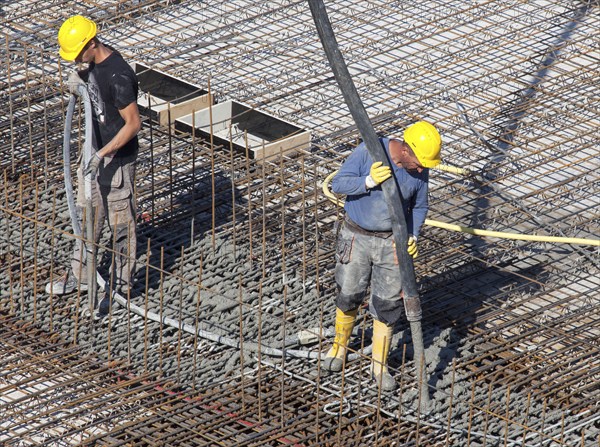 Construction workers backfilling concrete on a building site, Berlin, 19/08/2016