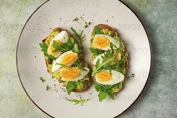 Sandwich with mashed avocado, boiled egg, and arugula, on bread, homemade, breakfast