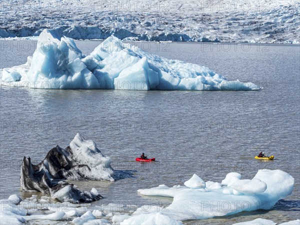 A group of tourists paddles in kayaks between icebergs, glacial lake Fjallsárlón, glacier Fjallsjökull, part of Vatnajökull glacier, Iceland, Europe