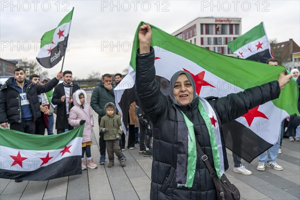 Syrian woman celebrate the end of the Assad regime after the change of power in Syria at a rally on the square in front of the main railway station in Duisburg, North Rhine-Westphalia, Germany, Europe