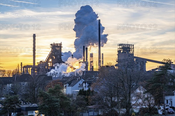 Blast furnace Schwelgern 1, Black Giant, Schwelgern 2 ThyssenKrupp Steel plant Schwelgern in Duisburg-Marxloh is part of the Bruckhausen steelworks, residential buildings in the Marxloh district, extinguishing cloud from the Schwelgern coking plant, sunset, North Rhine-Westphalia, Germany, Europe