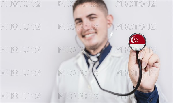 Smiling doctor showing stethoscope with Singapore flag. Singapore National Healthcare concept