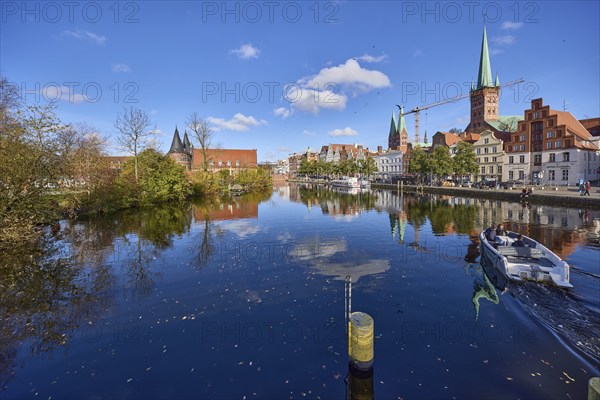 River Trave with quay wall, historic houses, Lübeck Holstentor, church towers of St. Marien and St. Petri, motorboat hire, reflection on the water surface, Hanseatic city of Lübeck, independent city, Schleswig-Holstein, Germany, Europe