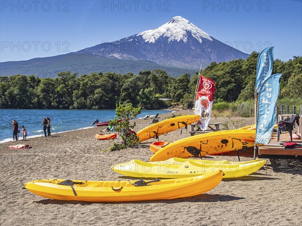 Beach in village Ensenada, lake Lago Llanquihue, view towards snowcovered volcano Osorno, summertime, people on the beach, sunbathing, swimming, kayaking, chilenean lake district, Chile, South America