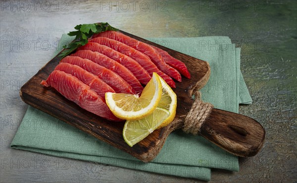 Chum salmon, cold smoked, sliced, on a cutting board, with lemon and parsley, top view, close-up, no people