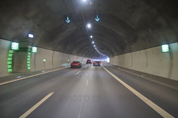 Cars drive through an illuminated concrete tunnel under shining lights, Switzerland, Europe