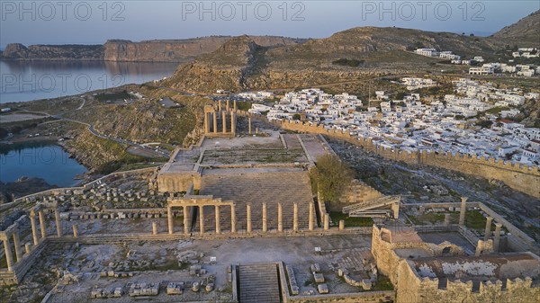 Drone shot, first morning light, Lindos, Acropolis of Lindos, Propylaea with flight of steps, Temple of Athena Lindia, Ruins of ancient columns on a cliff overlooking the sea at dusk, Archaeological site, Lindos, Rhodes, Dodecanese, Greek Islands, Greece, Europe