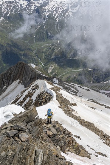 Mountaineer on a rocky ridge with snow, descent from the summit of the Schönbichler Horn, view of Tal Zemmgrund, Berliner Höhenweg, Zillertal Alps, Tyrol, Austria, Europe