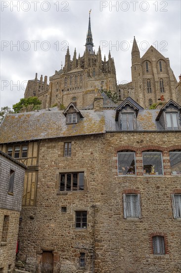 View of the Mont Saint-Michel buildings, dominated by towers and stone facades under a cloudy sky, Le Mont-Saint-Michel