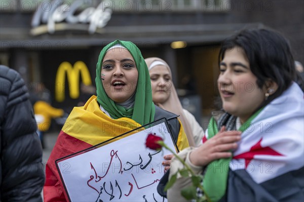 Syrian woman celebrate the end of the Assad regime after the change of power in Syria at a rally on the square in front of the main railway station in Duisburg, North Rhine-Westphalia, Germany, Europe