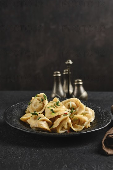 A black stone plate holds freshly made dumplings garnished with parsley, creating a delightful dish.