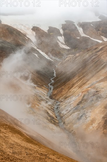 Steaming stream between colourful rhyolite mountains and snowfields, Hveradalir geothermal area, Kerlingarfjöll, Icelandic Highlands, Iceland, Europe