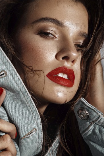 Beautiful sexy girl with bright makeup, red lips, wet hair in a denim jacket. Beauty face. Photo taken in studio