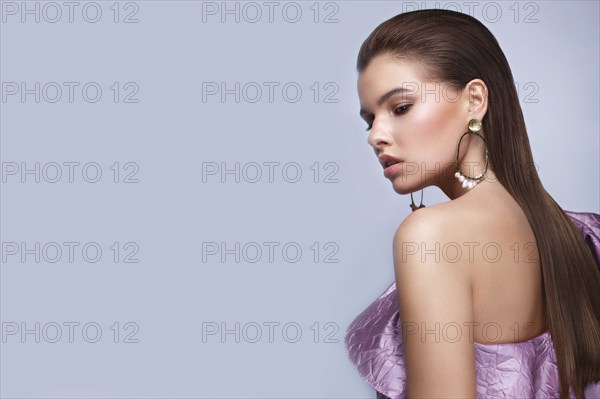 Beautiful fresh girl with classic make-up, smooth hair in a purple dress. Beauty face. Photo taken in studio