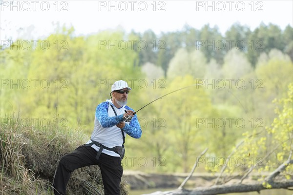 Fisherman trying to do a perfect cast, throwing lure. Spining fishing, angling, catching fish. Hobby and vacation. Photo with shallow depth of field taken at wide open aperture