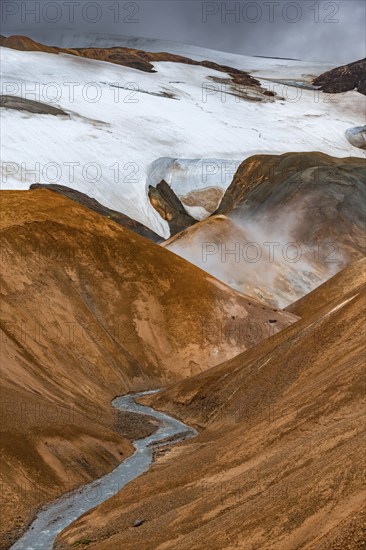 Steaming stream between colourful rhyolite mountains with snowfields, Hveradalir geothermal area, Kerlingarfjöll, Icelandic highlands, Iceland, Europe