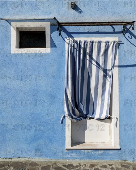 Blue house facade with entrance door with blue and white curtain and window, colourful houses on the island of Burano, Venice, Veneto, Italy, Europe