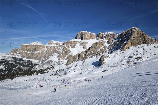 View of a ski resort piste with people skiing in Dolomites in Italy. Ski area Belvedere. Canazei, Italy, Europe