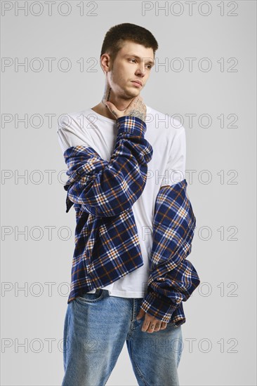 Young cocky man in checkered shirt and jeans touching his throat