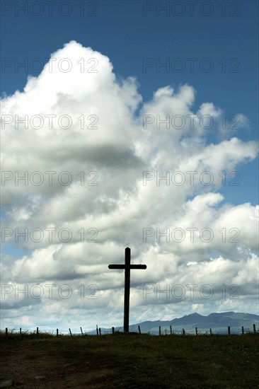 Wooden cross under a cloudy sky. Cezallier plateau. Puy de Dome departement. Auvergne-Rhone-Alpes. France