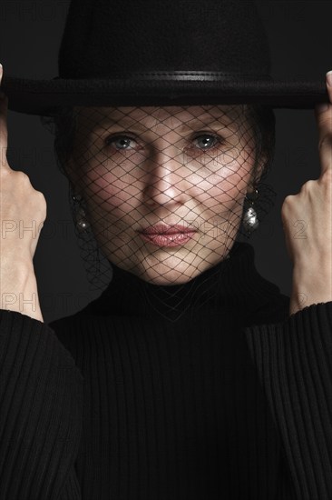 Portrait of a beautiful elderly woman in a white shirt with classic makeup and veil on the face