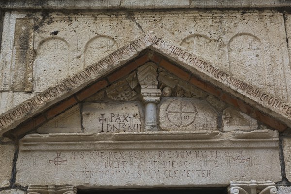 Close-up of carved letters and ancient symbols on old limestone building facade with triangular pediment at ancient 3rd century Roman ruins of Salona near Solin, Croatia, Europe