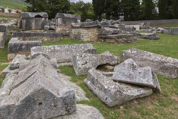 Close-up of old large and heavy broken pieces of cut and carved grey granite, stone and wall structures in cemetery at ancient 3rd century Roman ruins of Salona near Solin in late summer, Croatia, Europe