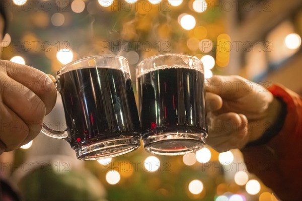 Two hands holding mulled wine cups in a festive night with lights, Lichternacht Fest, Nagold, Black Forest, Germany, Europe