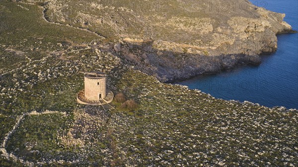 Drone shot, Lindos, late afternoon light, drone view of an old windmill on a rocky shore in the golden light of dusk, Archaeological site, Lindos, Rhodes, Dodecanese, Greek Islands, Greece, Europe