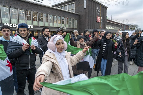 Syrian woman celebrate the end of the Assad regime after the change of power in Syria at a rally on the square in front of the main railway station in Duisburg, North Rhine-Westphalia, Germany, Europe