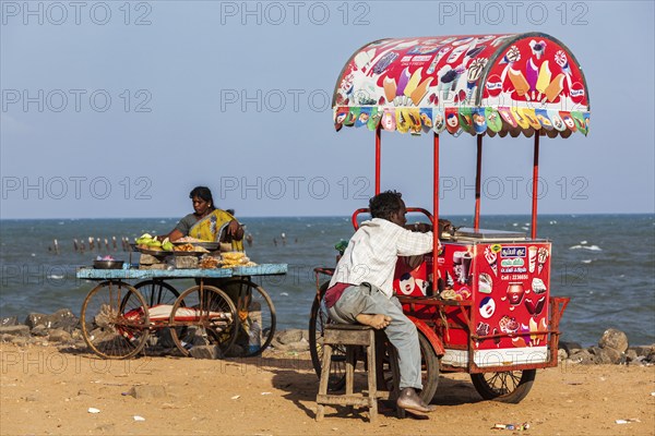 PONDICHERRY, INDIA, FEBRUARY 2, 2013: Unidentified Indian street vendors of ice cream and snacks with wheel carts on beach