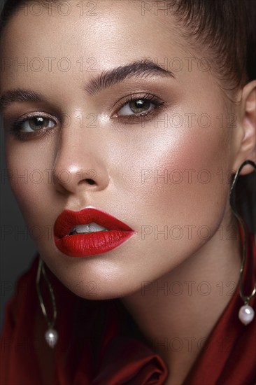 Beautiful fresh girl with classic make-up, smooth hair in a red dress. Beauty face. Photo taken in studio