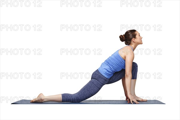 Beautiful sporty fit yogini woman practices yoga asana Anjaneyasana, low crescent lunge pose variation in surya namaskar in studio isolated on white