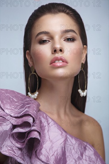 Beautiful fresh girl with classic make-up, smooth hair in a purple dress. Beauty face. Photo taken in studio