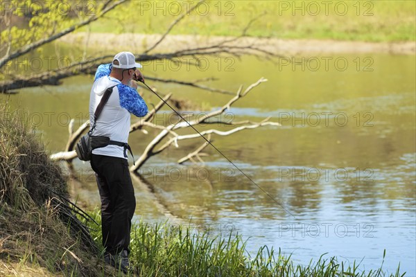 Fisherman trying to do a perfect cast, throwing lure. Spining fishing, angling, catching fish. Hobby and vacation. Photo with shallow depth of field taken at wide open aperture