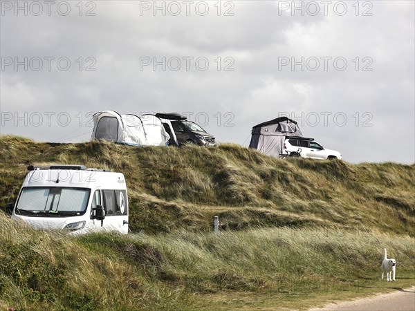 Motorhomes and an SUV with awning standing in the dunes of a campsite, Vejers, Denmark, 16.07.2023, Europe