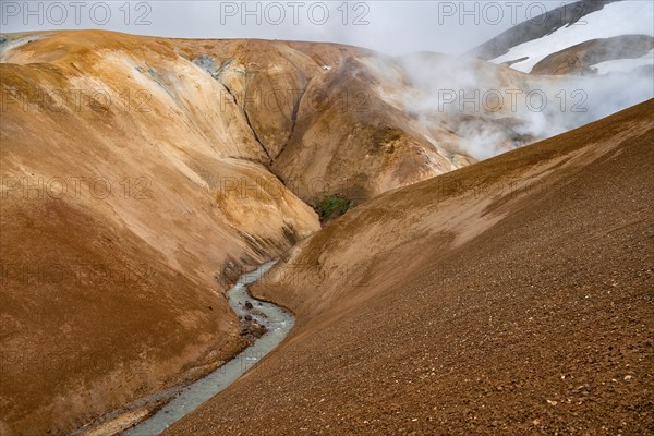 Steaming stream between colourful rhyolite mountains and snowfields, Hveradalir geothermal area, Kerlingarfjöll, Icelandic Highlands, Iceland, Europe