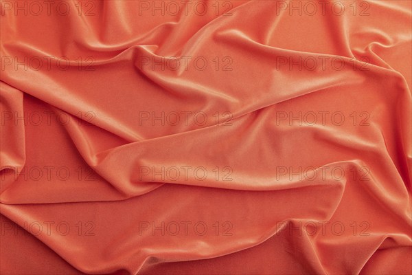 Fragment of red silk tissue. Top view, natural textile background and texture. wave concept, abstract