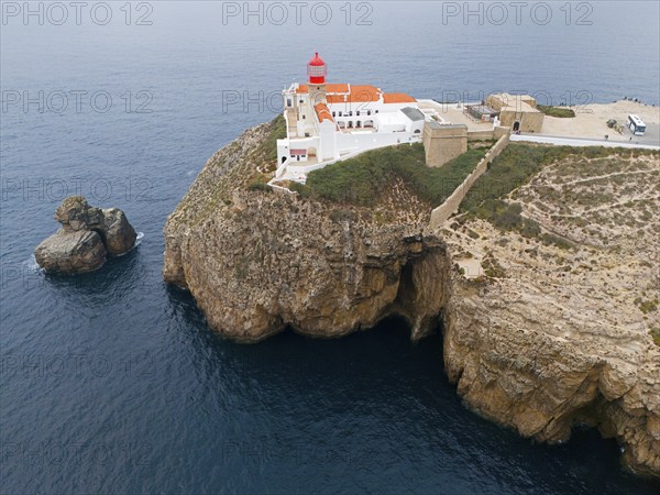 A red lighthouse and white buildings on a rocky cliff overlooking the ocean, an isolated feeling, aerial view, lighthouse, Cabo de São Vicente, Cape St Vincent, Cape St Vincent, Sagres, Portugal, Europe